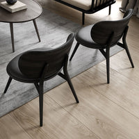 Elegant dark wood chairs with curved backs, set against a soft gray rug and light brown floor. Modern minimalist design.