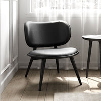 Black leather chair with a sleek, minimalist design and smooth, rounded patterns, set against a light, airy backdrop.