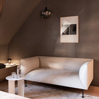 Stylish cream sofa with curved edges on a textured beige rug, complementing a neutral-toned wall and contemporary decor.