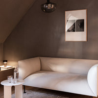 Soft white curved sofa in a neutral-toned room, featuring clean lines and modern minimalist decor.
