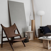 Brown leather chair with minimalist design, gray backdrop, neutral-toned decor, and subtle modern textures.