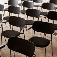 Black molded chairs arranged in rows, featuring minimalist design on a neutral textured floor.