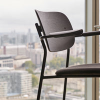 Modern black chair with sleek lines and a minimalist design, set against a city skyline backdrop.