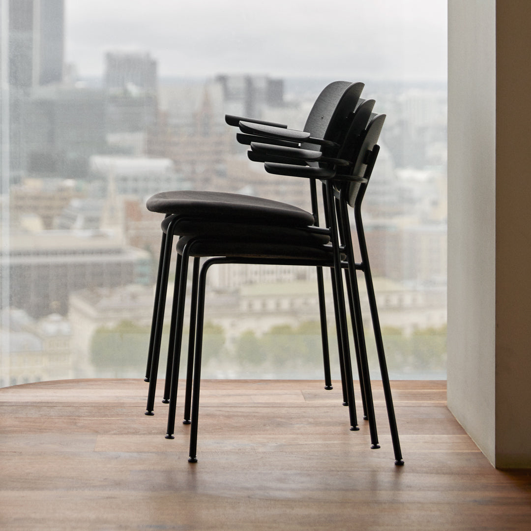 Stacked black chairs with minimalist design, showcasing a sleek, modern aesthetic against a city backdrop.