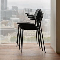 Stacked black chairs with minimalist design, showcasing a sleek, modern aesthetic against a city backdrop.