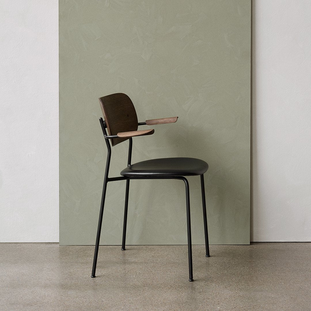 Stylish black and brown chair with a minimalist design against a smooth green backdrop. Modern and sleek aesthetic.