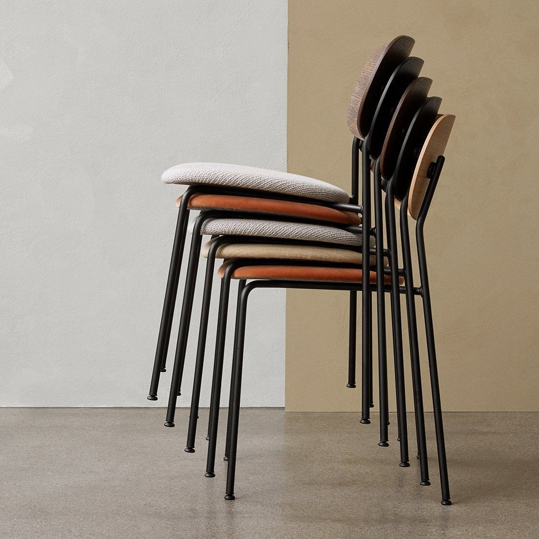 Stacked chairs featuring a mix of light grey, beige, and warm wooden tones with sleek black metal frames.
