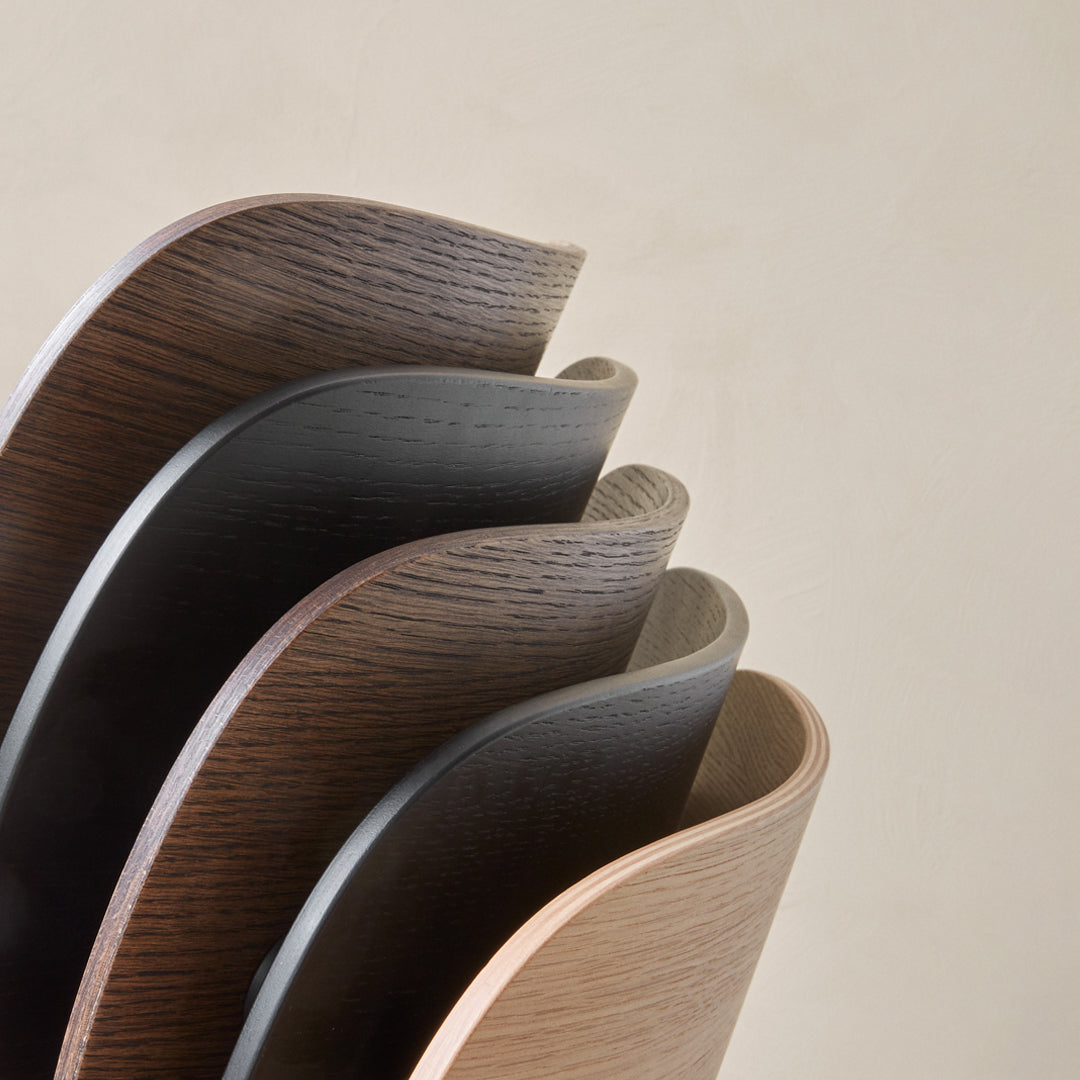 Stacked curved wood panels in rich brown, black, and light wood tones with smooth finishes and subtle textures.