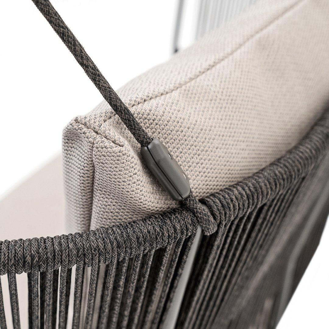 Gray woven chair with a soft beige cushion, featuring sleek black accents and a unique linear pattern.