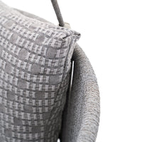 Gray woven cushion with a textured pattern, featuring a mix of check and dot designs, on a curved gray chair.