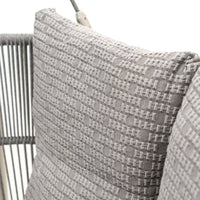 Gray textured pillow with a woven pattern, accented by a soft, neutral color palette on a stylish modern chair.