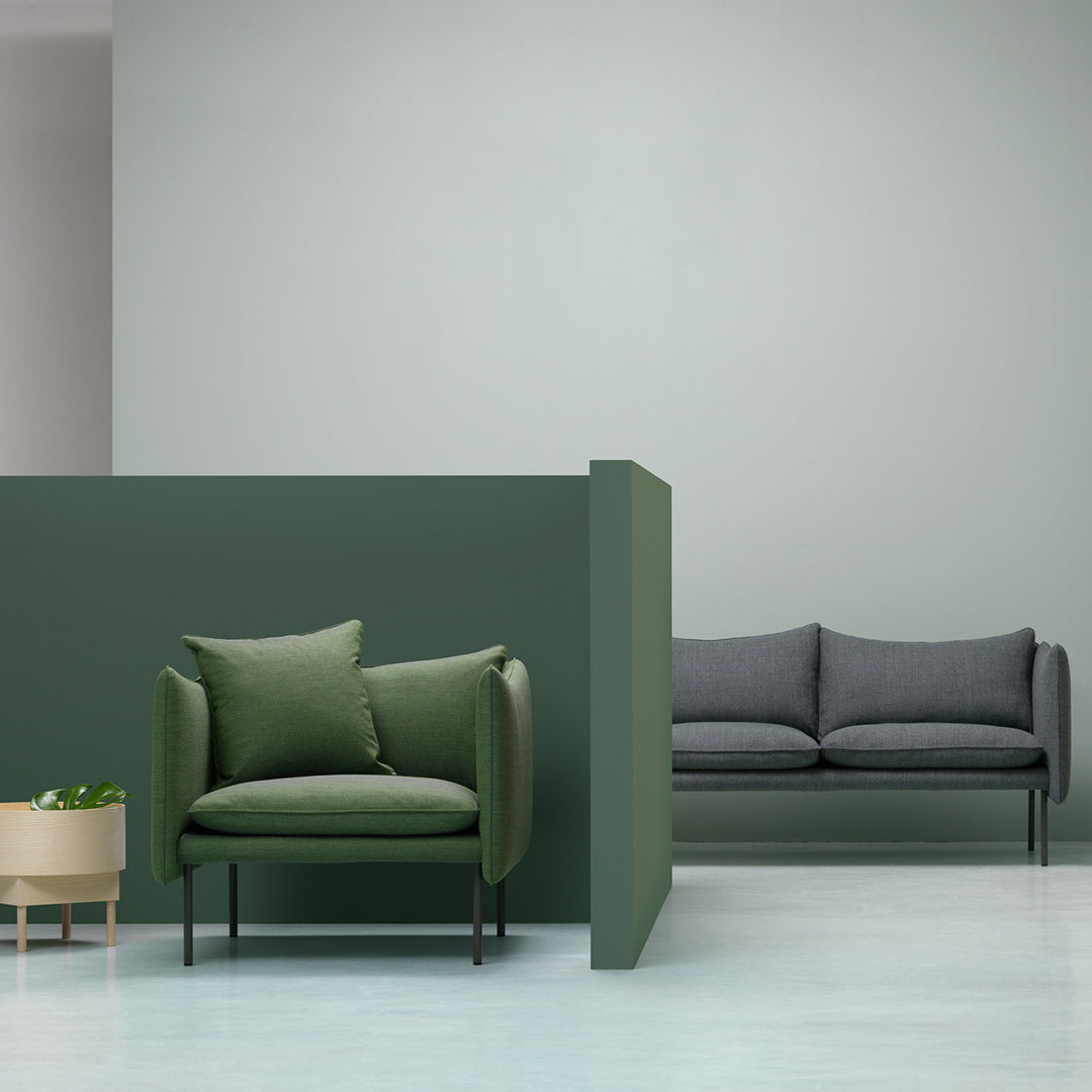 Green and gray upholstered sofa set against soft green and gray walls, creating a modern, calming aesthetic.