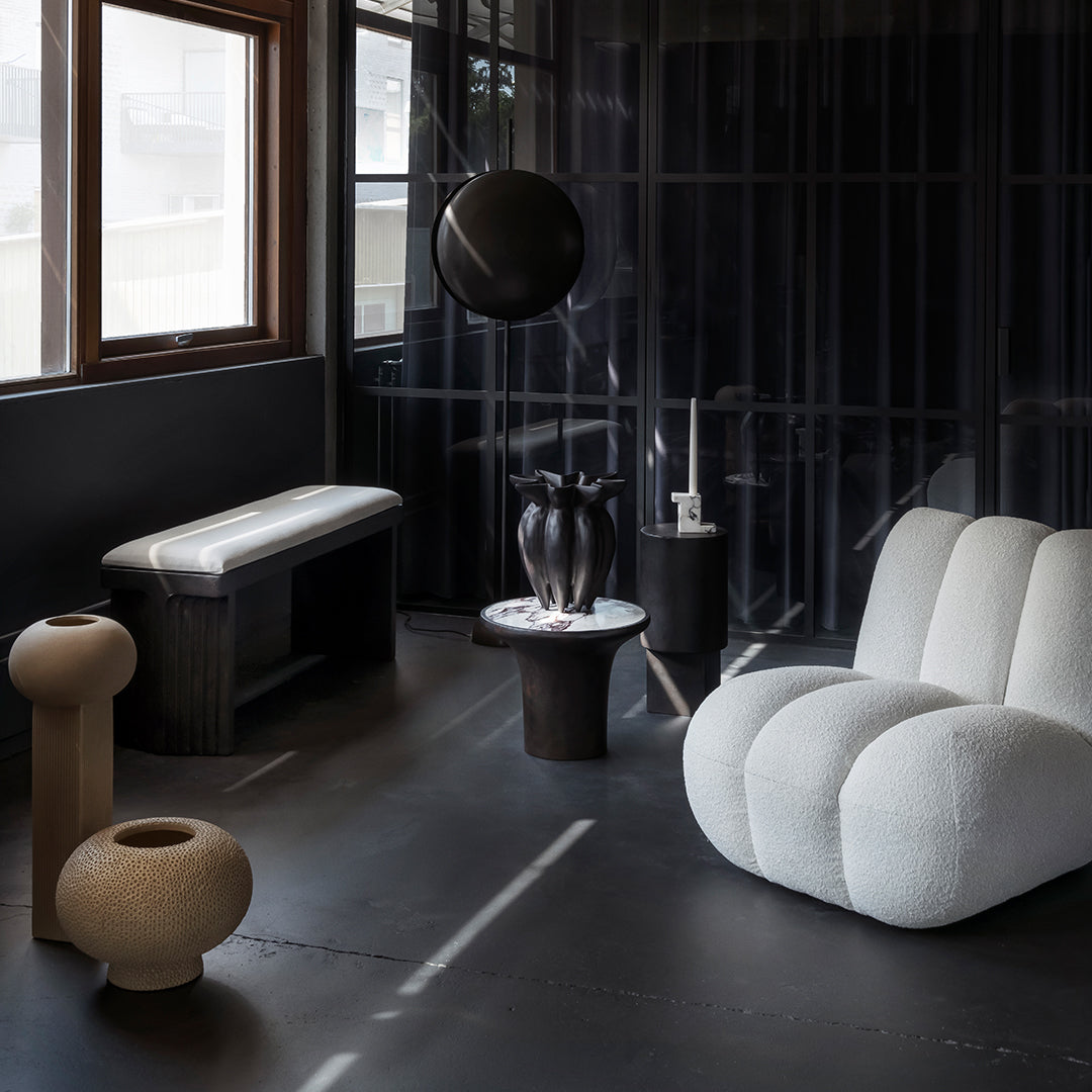 "Neutral-toned furniture with textured fabrics and sleek black accents in a modern interior setting."