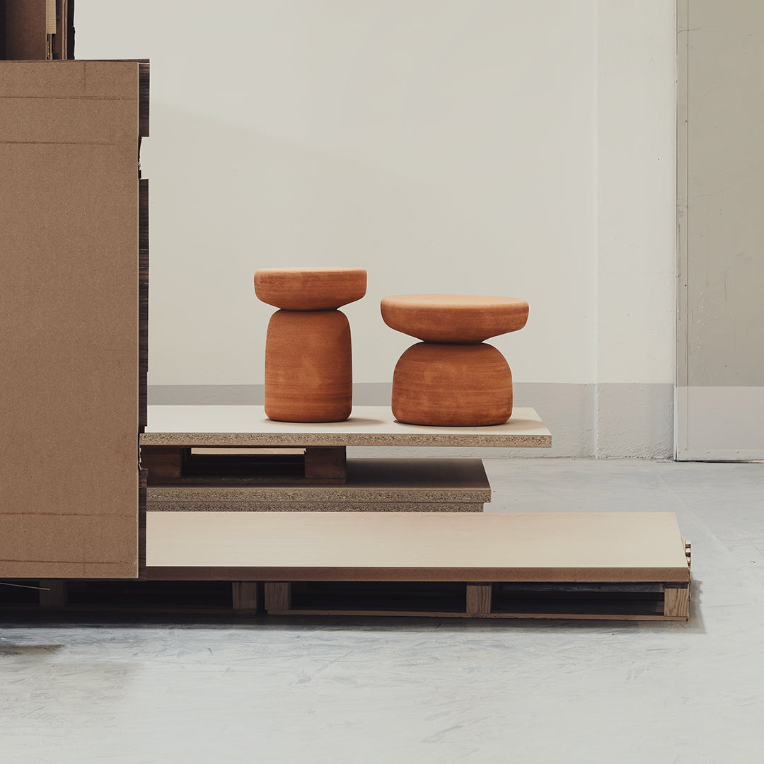 Terra cotta stools on a minimalist wooden platform with neutral tones and clean lines.