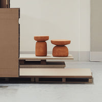 Terra cotta stools on a minimalist wooden platform with neutral tones and clean lines.
