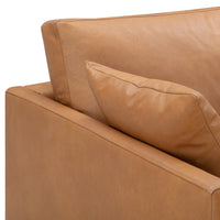 Tan leather sectional sofa with smooth texture and a matching throw pillow in a modern, minimalist design.