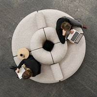 Light gray circular sofa with modular sections and a unique rounded design, featuring soft, textured upholstery.