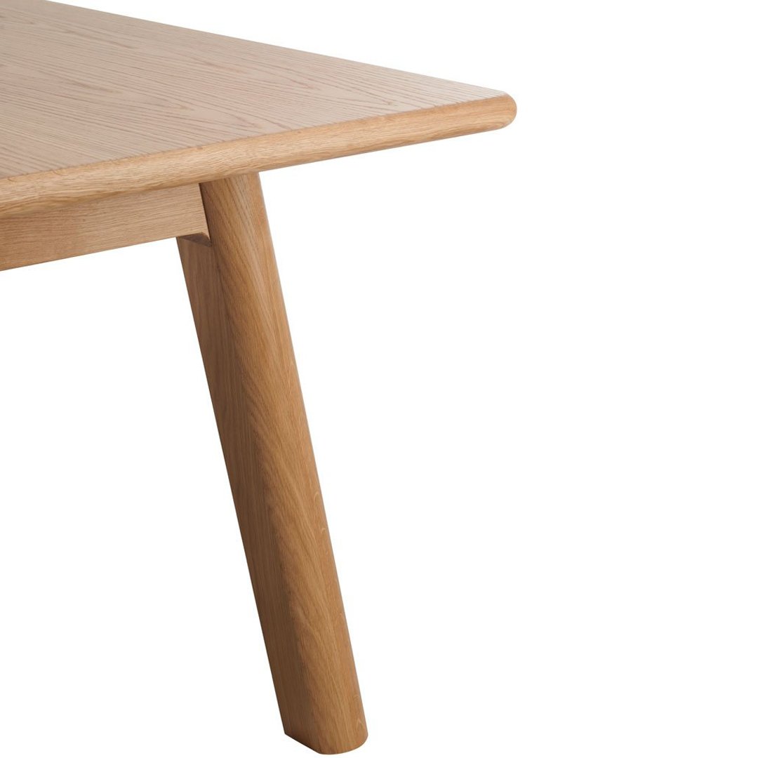 Natural light oak wood table with a smooth finish and sleek, tapered legs. Elegant minimalist design and warm tones.
