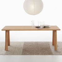 Light wood dining table on a neutral-toned rug, featuring a soft, natural texture. Minimalist design with sleek lines.