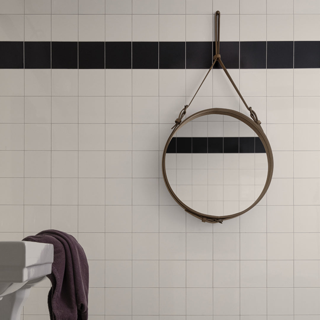 Round mirror with a leather strap, featuring a grid of white tiles and dark blue horizontal accents.
