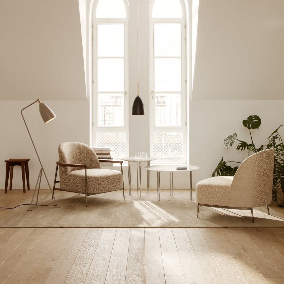 Beige armchairs with textured fabric in a bright, minimalistic room, complemented by light wood flooring and greenery.