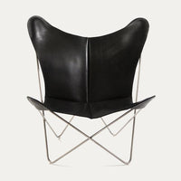 Black leather butterfly chair with sleek, minimalist design and stainless steel frame, showcasing a modern aesthetic.