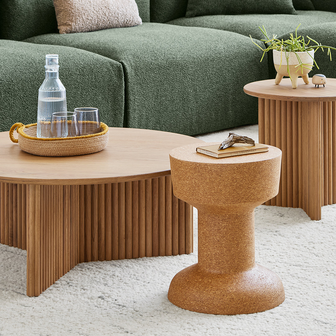 Natural wood tones, earthy cork texture, and soft green upholstery create a harmonious and modern living space.