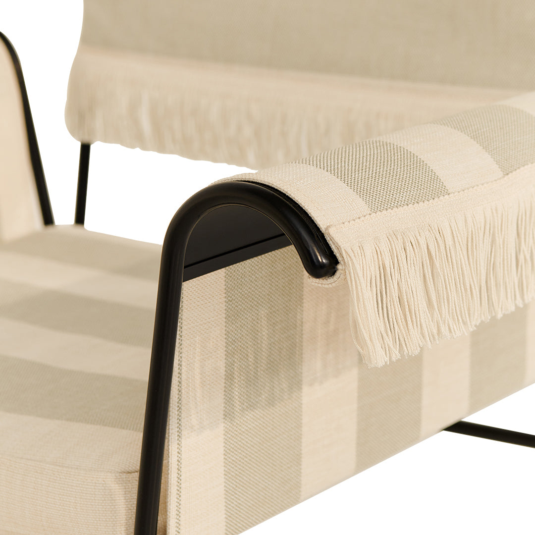 Beige striped fabric with fringed edges on a modern lounge chair, showcasing a minimalistic design and sleek black accents.