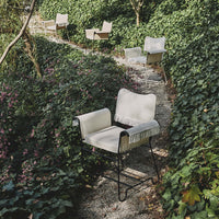 Light beige chairs with subtle textured patterns, framed by lush greenery and vibrant purple flowers.