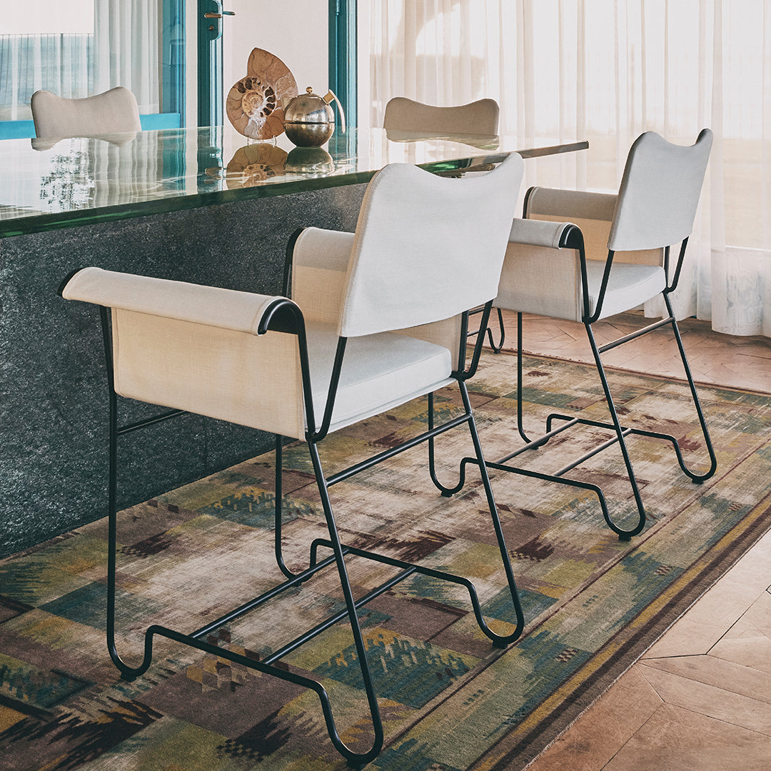 White and wood dining chairs with black metal legs on a patterned area rug featuring earthy tones and geometric designs.