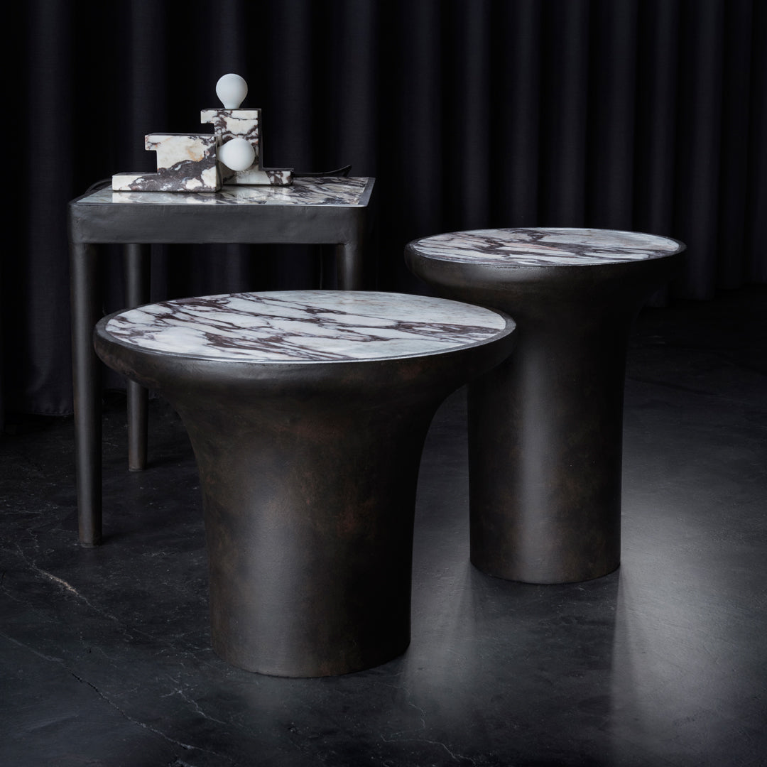 "Stylish round tables with dark bases and elegant white marble tops featuring bold black veining."