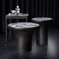 "Stylish round tables with dark bases and elegant white marble tops featuring bold black veining."