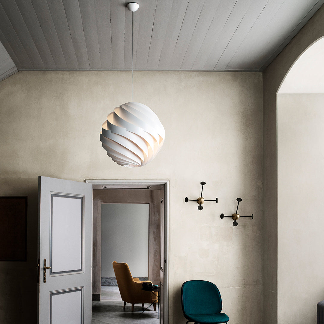 White spiral pendant light against a neutral wall, featuring soft curves and a minimalist design. Perfect for modern decor.