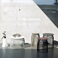 Multi-colored wire side tables with sleek patterns, featuring white, pink, gold, and black finishes against a modern backdrop.