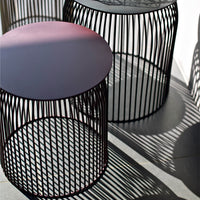 Two modern wire side tables in black with sleek round tops and unique shadow patterns. Ideal for contemporary decor.