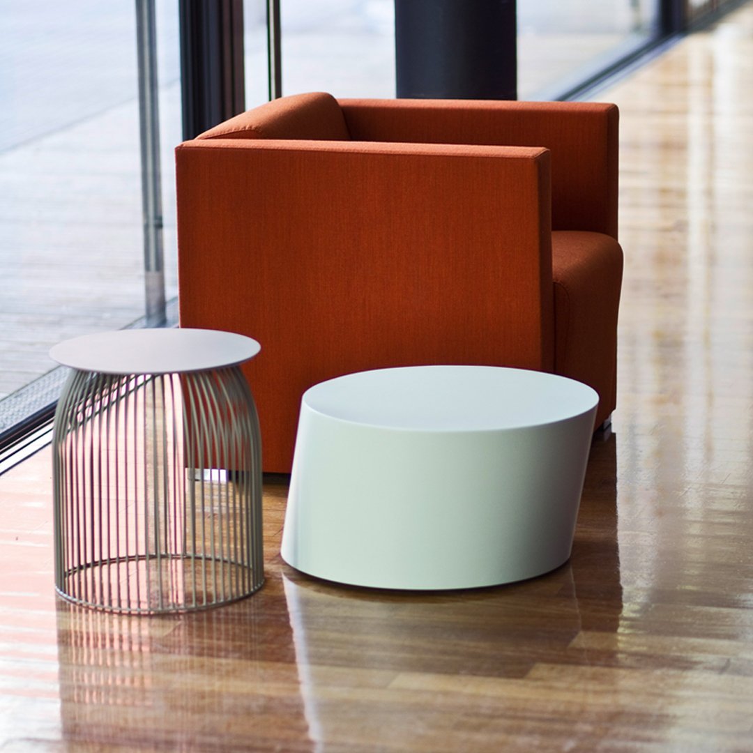 Orange upholstered chair, white round and wire accent tables, modern design, contrasting colors, sleek patterns.