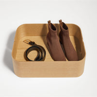 Brown ankle boots paired with a black belt, displayed in a light wooden tray on a white background.