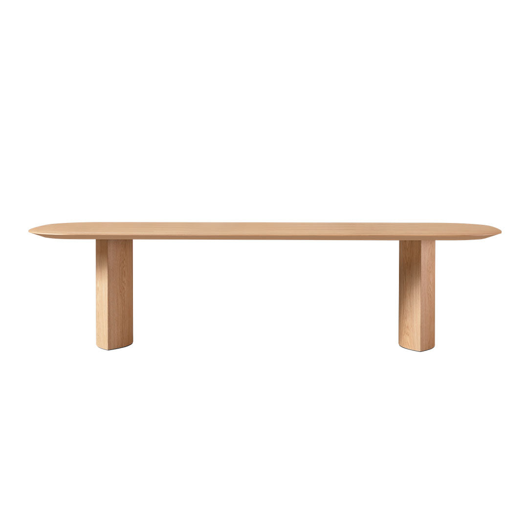 Light oak wood bench with a smooth, oval top and minimalist cylindrical legs. Natural finish, no distinct patterns.