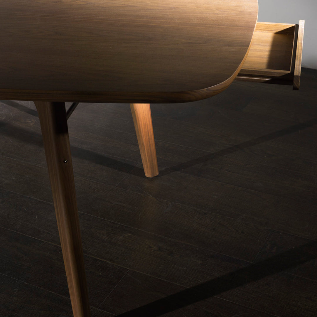Light wood table with smooth curves and natural grain, featuring a sleek design against a dark wood floor background.