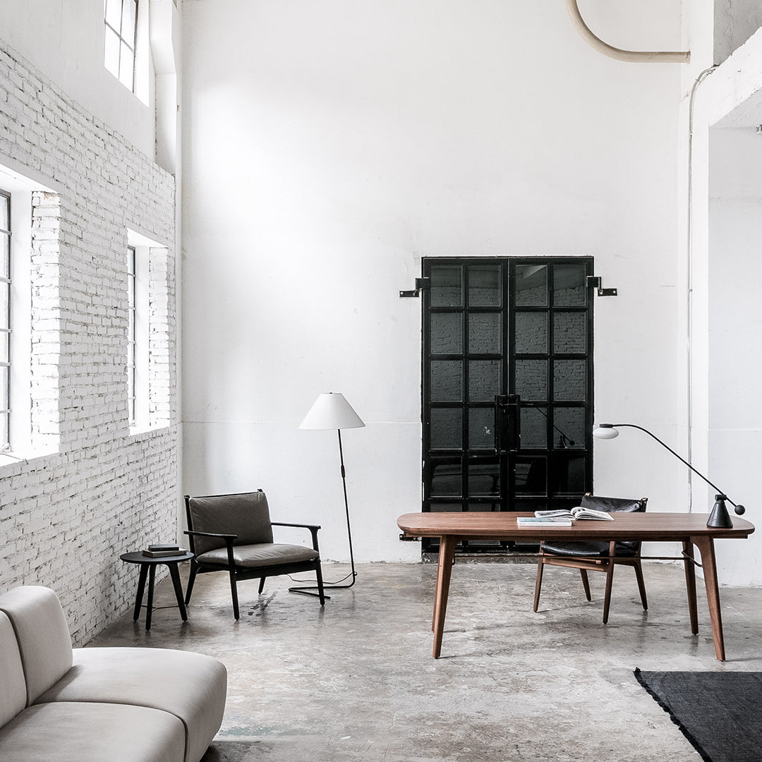 Modern office setup with white walls, black accents, natural wood tones, and a gray textured floor.