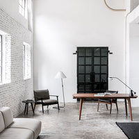 Modern office setup with white walls, black accents, natural wood tones, and a gray textured floor.