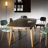 Mid-century modern dining table in natural wood finish with black and green upholstered chairs, set against a neutral backdrop.