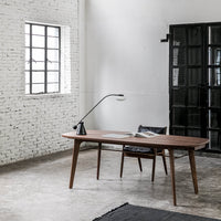Mid-century walnut desk with sleek lines, complemented by a black chair and minimalistic patterns in a modern interior setting.