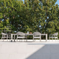 Modern outdoor dining set featuring sleek gray furniture against a backdrop of lush green trees and vibrant sunlight.
