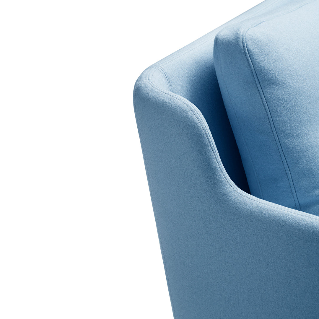 Light blue upholstered armchair corner with smooth, modern lines and soft cushion. Ideal for stylish living spaces.
