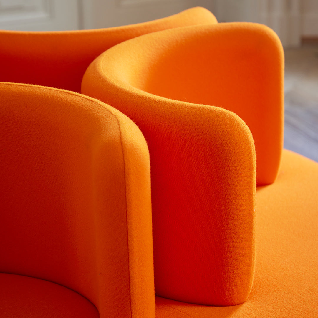 Bright orange armchair with soft, curved upholstery, showcasing a modern design and vibrant color.
