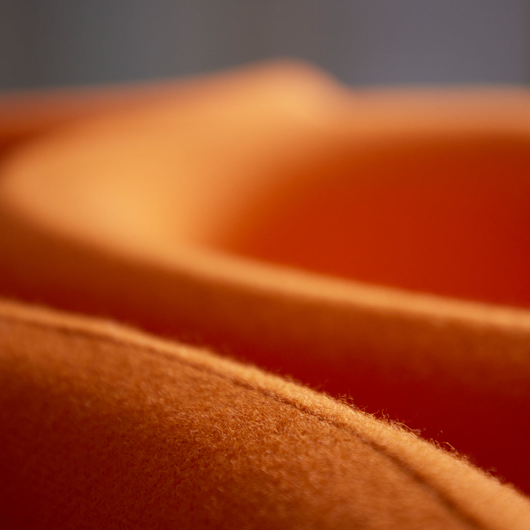 Close-up of soft, textured fabric in shades of warm orange, showcasing smooth curves and a cozy feel.