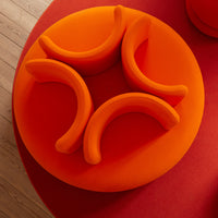 Vibrant orange seating with smooth curves, set against a contrasting red background, creating a stylish modern look.