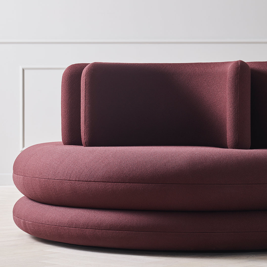 Burgundy upholstered sofa with smooth, rounded shapes and a minimalist design. Modern and stylish home decor accent.