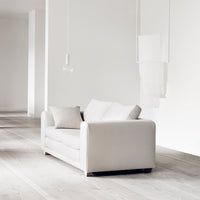 "Soft white sofa with clean lines and a minimalist design, complemented by a light wooden floor."